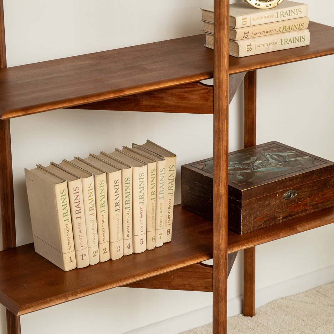 Wooden bookshelf with books and decorative items against a white wall.
