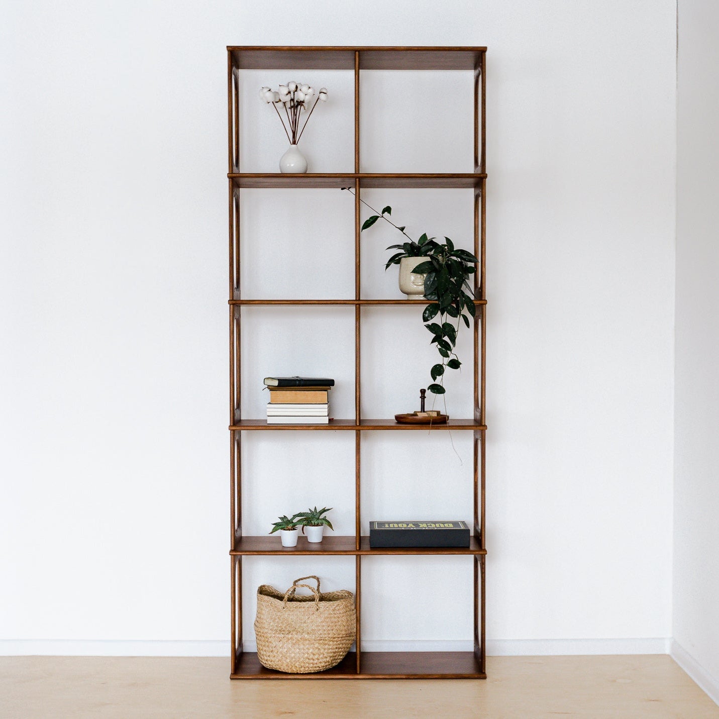 Wooden bookshelf with decorative items against a white wall