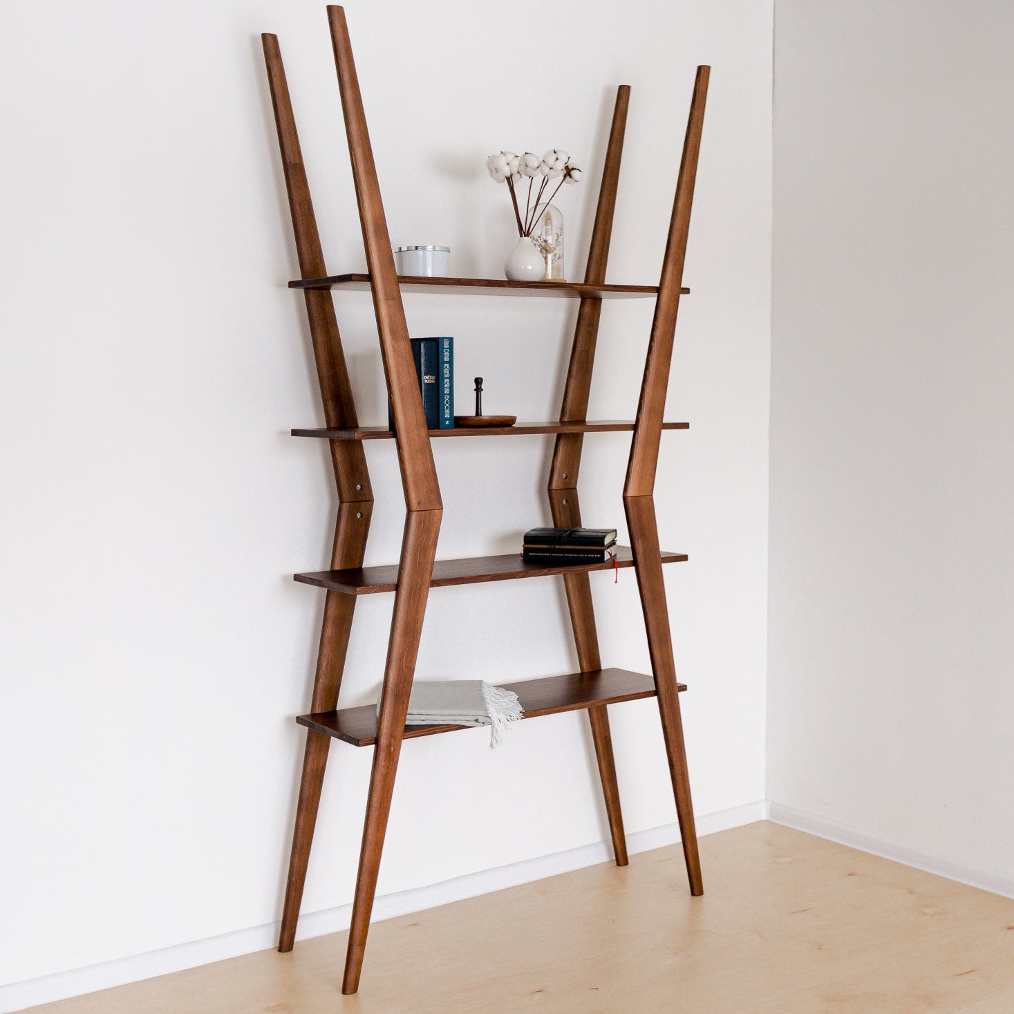 Wooden ladder shelf against a white wall with minimal decor.